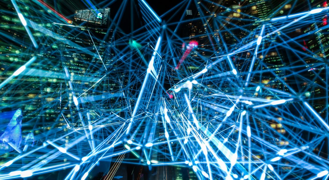 都会の夜景を背景に、青い光の線が複雑に絡み合い、ネットワークや情報伝達の様子を表現している。協立情報通信が提供するICTソリューションや情報通信技術の融合によるデジタル化の推進を象徴する。