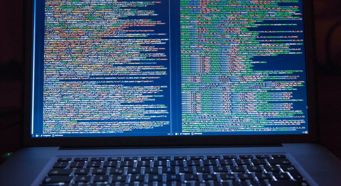 ノートパソコンの画面に表示された複雑なプログラミングコード。社会インフラや「ものづくり」をICTで支える菱友システムズの高度な専門技術と時代に即応した最適なITソリューション提供を象徴している。