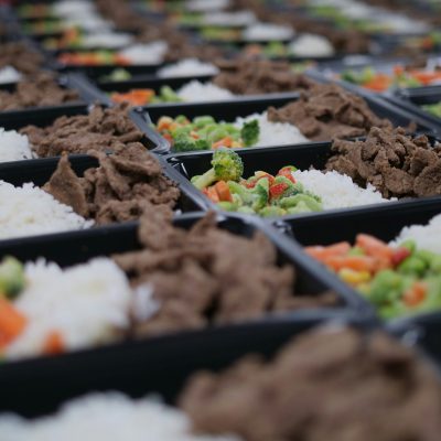 様々な食品が詰められたプラスチック製弁当容器の数々。エフピコが国内食品容器の最大手として、年間2,000以上の新製品開発を行い、食品トレーのリサイクルで業界をリードしながら、日本の食生活を彩る製品を提供していることを示唆しています。